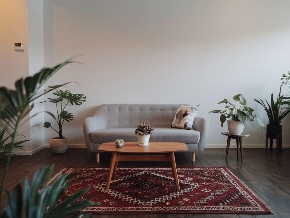 Dywan w jasnych odcieniach podkreślający szarą kanapę